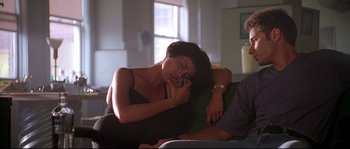 Movie still from “Kalifornia” (1993), directed by Dominic Sena – A woman sitting on top of a couch while talking on a cell phone; Medium shot, Low angle