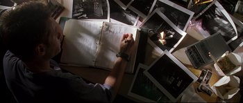 Movie still from “Kalifornia” (1993), directed by Dominic Sena – A person writing in a book on top of a table; Close Up shot, High angle
