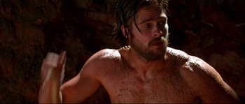 Movie still from “Kalifornia” (1993), directed by Dominic Sena – A man with a beard is standing in a cave; Close Up shot, Over the shoulder angle