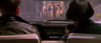 Movie still from “Kalifornia” (1993), directed by Dominic Sena – Two people standing in front of an open door in a building; Wide shot, Over the shoulder angle