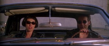 Movie still from “Kalifornia” (1993), directed by Dominic Sena – A woman sitting in the driver's seat of a car; Medium shot, Low angle