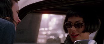 Movie still from “Kalifornia” (1993), directed by Dominic Sena – A woman with sunglasses is standing under an umbrella; Close Up shot, Over the shoulder angle
