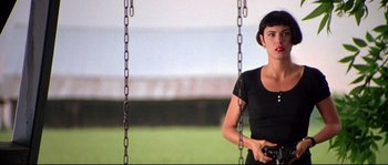 Movie still from “Kalifornia” (1993), directed by Dominic Sena – A woman holding a camera while sitting on a swing; Medium shot, Low angle
