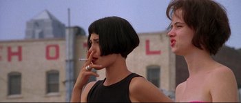 Movie still from “Kalifornia” (1993), directed by Dominic Sena – A woman smoking a cigarette in front of a building; Close Up shot, Low angle