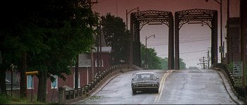 Movie still from “Kalifornia” (1993), directed by Dominic Sena – A car driving down a street under a bridge; Extreme Wide shot, High angle