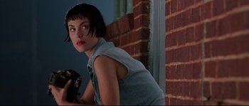 Movie still from “Kalifornia” (1993), directed by Dominic Sena – A woman with short black hair is leaning against a brick wall; Close Up shot, Low angle