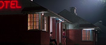 Movie still from “Kalifornia” (1993), directed by Dominic Sena – A couple of people that are standing in front of a building; Extreme Wide shot, Low angle