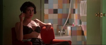 Movie still from “Kalifornia” (1993), directed by Dominic Sena – A woman sitting on a red chair in front of a colorful wall; Medium shot, Low angle