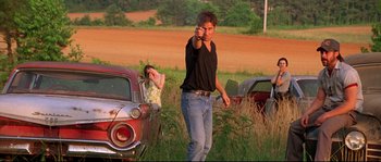 Movie still from “Kalifornia” (1993), directed by Dominic Sena – A man and a woman standing in a field near old cars; Medium shot, Low angle