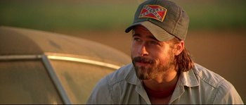 Movie still from “Kalifornia” (1993), directed by Dominic Sena – A man with a beard wearing a baseball cap; Close Up shot, Over the shoulder angle