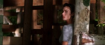 Movie still from “Kalifornia” (1993), directed by Dominic Sena – A beautiful woman standing next to a wooden wall; Close Up shot, Low angle