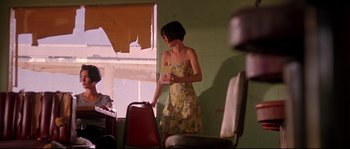 Movie still from “Kalifornia” (1993), directed by Dominic Sena – A woman in a yellow dress standing in front of a window; Medium shot, Low angle