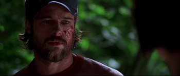 Movie still from “Kalifornia” (1993), directed by Dominic Sena – A person wearing a baseball cap with blood all over his face; Close Up shot, Over the shoulder angle