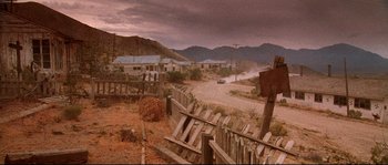 Movie still from “Kalifornia” (1993), directed by Dominic Sena – An abandoned town with a wooden fence in the foreground and mountains in the background; Extreme Wide shot, Low angle