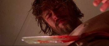 Movie still from “Kalifornia” (1993), directed by Dominic Sena – A man with a beard is holding a bloody knife in his hand; Close Up shot, Low angle