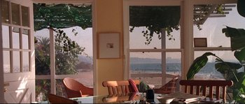 Movie still from “Kalifornia” (1993), directed by Dominic Sena – A room with a view of the ocean and a table with two chairs; Wide shot, High angle