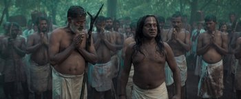 Movie still from “Kantara” (2022), directed by Rishab Shetty – A group of men standing next to each other in the woods; Medium shot, Low angle
