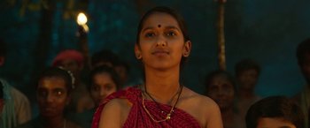 Movie still from “Kantara” (2022), directed by Rishab Shetty – A young woman in a red sari is looking up; Close Up shot, Low angle