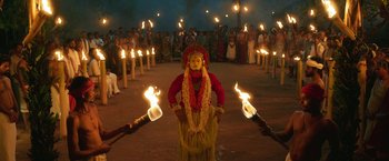 Movie still from “Kantara” (2022), directed by Rishab Shetty – A man in a red and white costume holding a fire; Extreme Wide shot, High angle