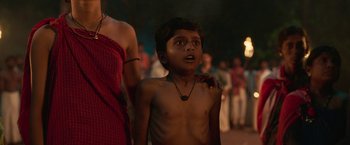 Movie still from “Kantara” (2022), directed by Rishab Shetty – A young boy is standing in front of a group of people; Close Up shot, Low angle