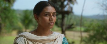 Movie still from “Kantara” (2022), directed by Rishab Shetty – A woman in a blue and white dress is looking at the camera; Close Up shot, Low angle