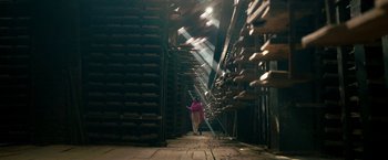 Movie still from “Kantara” (2022), directed by Rishab Shetty – A person walking in a room filled with stacks of shoes; Wide shot, Low angle