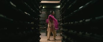 Movie still from “Kantara” (2022), directed by Rishab Shetty – A woman in a pink shawl standing in a room; Wide shot, Low angle