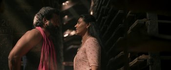 Movie still from “Kantara” (2022), directed by Rishab Shetty – A man and a woman standing next to each other; Medium shot, Low angle