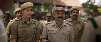 Movie still from “Kantara” (2022), directed by Rishab Shetty – A group of men in uniform standing next to each other; Medium shot, Over the shoulder angle