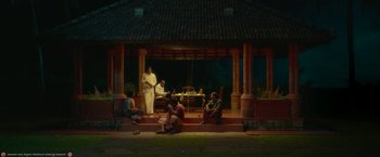 Movie still from “Kantara” (2022), directed by Rishab Shetty – A group of people sitting on steps in front of a building; Extreme Wide shot, High angle