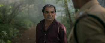 Movie still from “Kantara” (2022), directed by Rishab Shetty – A person wearing a maroon shirt; Close Up shot, Over the shoulder angle