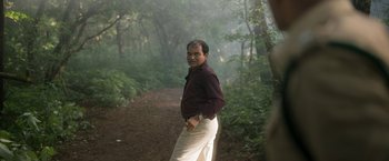 Movie still from “Kantara” (2022), directed by Rishab Shetty – A man standing in the middle of a path in the woods; Medium shot, Low angle