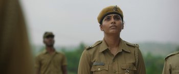 Movie still from “Kantara” (2022), directed by Rishab Shetty – A woman in a uniform looking up at something; Close Up shot, Low angle
