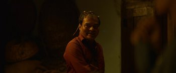 Movie still from “Kantara” (2022), directed by Rishab Shetty – A man wearing a red shirt and a headband; Close Up shot, Over the shoulder angle