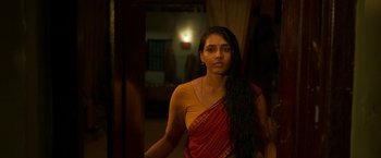 Movie still from “Kantara” (2022), directed by Rishab Shetty – A woman in a red and yellow sari standing next to a doorway; Close Up shot, Over the shoulder angle