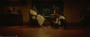 Movie still from “Kantara” (2022), directed by Rishab Shetty – A group of men sitting on a floor playing a game; Wide shot, High angle