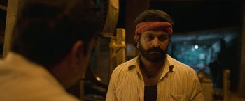 Movie still from “Kantara” (2022), directed by Rishab Shetty – A man with a red bandanna on his head; Close Up shot, Low angle