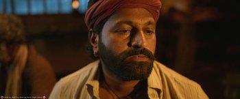 Movie still from “Kantara” (2022), directed by Rishab Shetty – A person with a beard wearing a turban; Close Up shot, Low angle