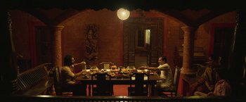 Movie still from “Kantara” (2022), directed by Rishab Shetty – A group of people sitting at a dinner table; Wide shot, High angle