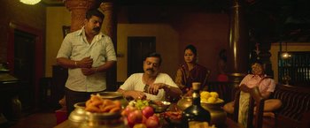 Movie still from “Kantara” (2022), directed by Rishab Shetty – A group of people sitting around a table with food; Wide shot, Low angle