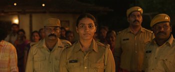 Movie still from “Kantara” (2022), directed by Rishab Shetty – A woman in a uniform standing in front of a group of people; Close Up shot, Over the shoulder angle