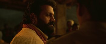 Movie still from “Kantara” (2022), directed by Rishab Shetty – A man with a goatee is looking into the distance; Close Up shot, Low angle