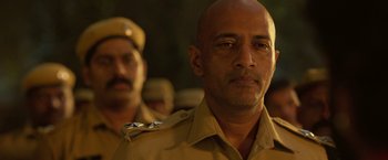 Movie still from “Kantara” (2022), directed by Rishab Shetty – A person wearing a uniform; Close Up shot, Low angle