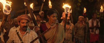 Movie still from “Kantara” (2022), directed by Rishab Shetty – A group of people holding torches in the dark; Medium shot, Low angle