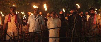 Movie still from “Kantara” (2022), directed by Rishab Shetty – A group of men holding torches in front of each other; Wide shot, Low angle