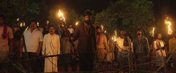 Movie still from “Kantara” (2022), directed by Rishab Shetty – A group of men holding torches in a dark area; Wide shot, Low angle