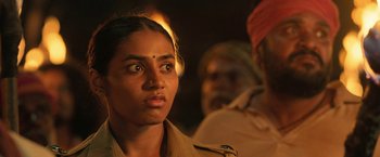 Movie still from “Kantara” (2022), directed by Rishab Shetty – A person with a person in the background; Close Up shot, Over the shoulder angle