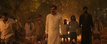 Movie still from “Kantara” (2022), directed by Rishab Shetty – A group of men standing next to each other in front of a tree; Medium shot, Low angle