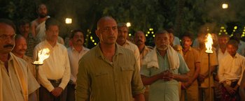 Movie still from “Kantara” (2022), directed by Rishab Shetty – A group of men standing next to each other in front of trees; Medium shot, Low angle