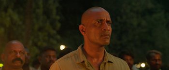 Movie still from “Kantara” (2022), directed by Rishab Shetty – A man with a bald head is looking into the distance; Close Up shot, Low angle